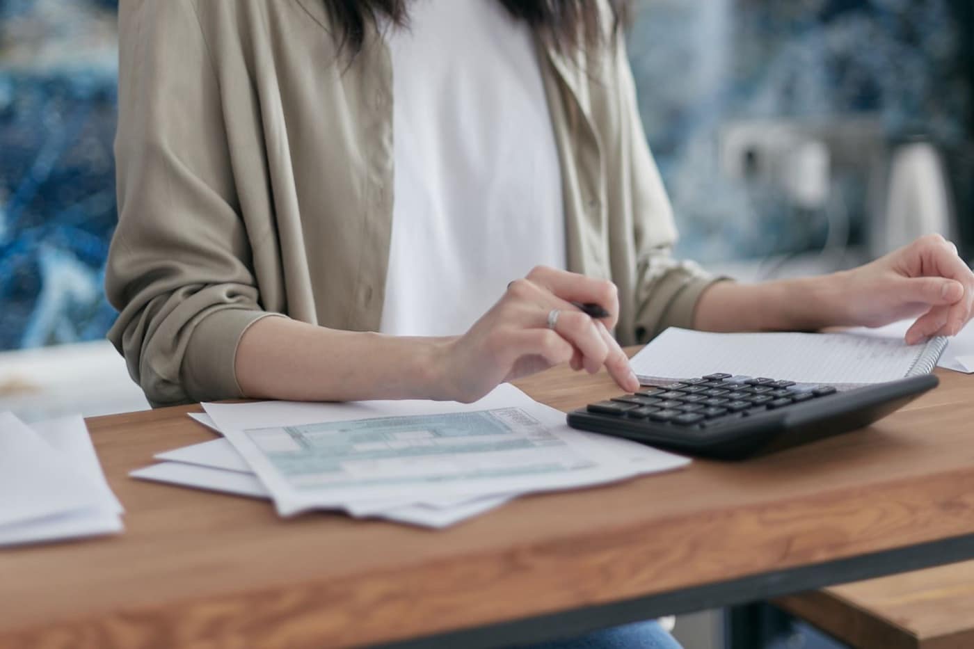 Persona repasando facturas y documentación con una calculadora sobre la mesa